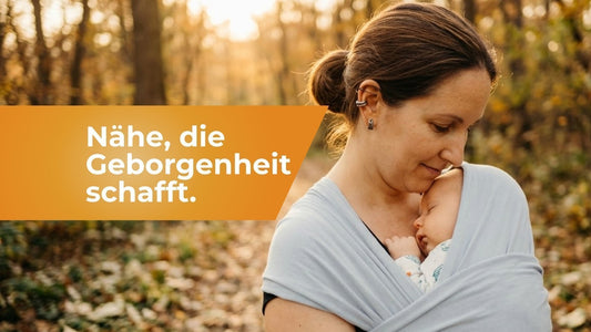 Elternteil trägt Baby in ergonomischer Babytrage im Wald, das Baby schläft friedlich auf der Brust. Förderung der emotionalen Bindung und des Urvertrauens.